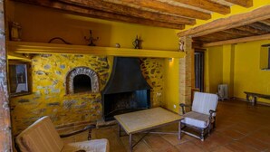 Une pièce rustique avec un mur en pierre, une cheminée et des meubles en bois.