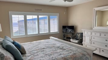 Een slaapkamer met een groot bed, een dressoir, een televisie en een plafondventilator.