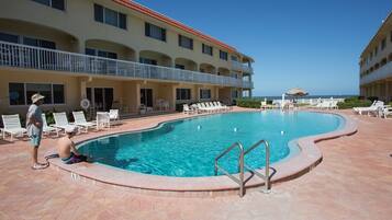 A swimming pool with a tiled deck, a lifeguard stand, and a view of the ocean.