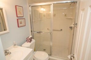 Bathroom features a glass-enclosed shower, white sink, toilet, and bathtub.