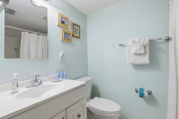 A bathroom with a white sink, a mirror, a toilet, and a towel rack.