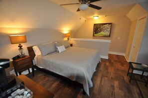 A bedroom with a bed, bedside lamps, a ceiling fan, a painting on the wall, and a wooden floor. - The Riverland Loft in Charleston, SC (Charleston)