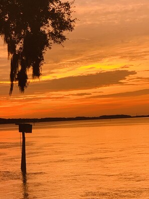 A sunset over a calm body of water with a wooden post in the foreground. - The Riverland Loft in Charleston, SC (Charleston)