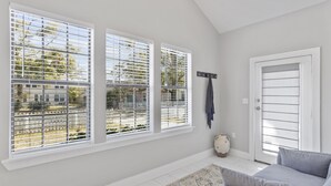 Una habitación con ventanas amplias, una puerta y un sofá gris.