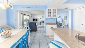 A compact kitchen with a dining area, a TV, and a small living room. - Errol by the Sea unit 125- 2BD - Beachy Keen (New Smyrna Beach)