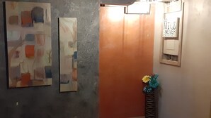Un couloir orné de peintures abstraites, une porte en bois et une pancarte sur laquelle on peut lire : « GO MILE, jamais bondé ».