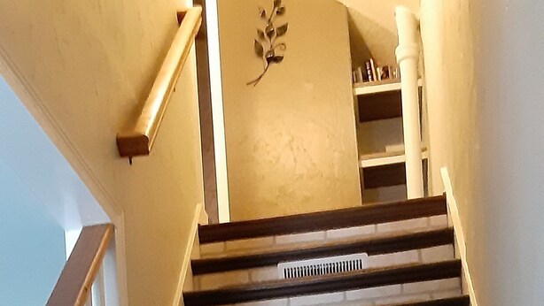 Un escalier avec des marches en bois et des murs en briques blanches.