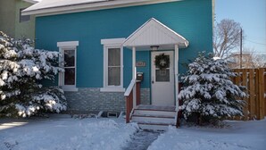 Une maison à deux étages, avec une façade bleue, un porche à l’avant et une boîte aux lettres.