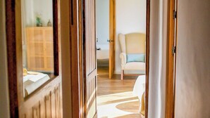 A room with a wooden floor, a white chair, and a wooden cabinet in the background. - Almez De Lúa Güéjar Sierra by Ruralidays (Granada)