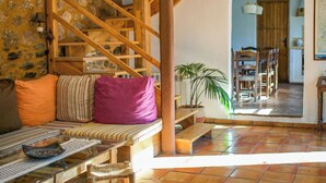 A cozy living area with a wooden staircase, a bench, and a dining table with chairs. - Almez De Lúa Güéjar Sierra by Ruralidays (Granada)