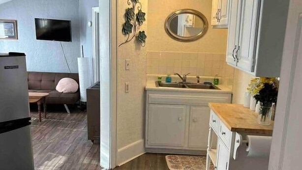 Una cocina compacta con armarios blancos, una encimera de madera y un horno integrado.