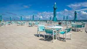 A rooftop terrace with outdoor seating and umbrellas. - Errol by the Sea - Unit 107 - 1BD - The Salty Nest (New Smyrna Beach)