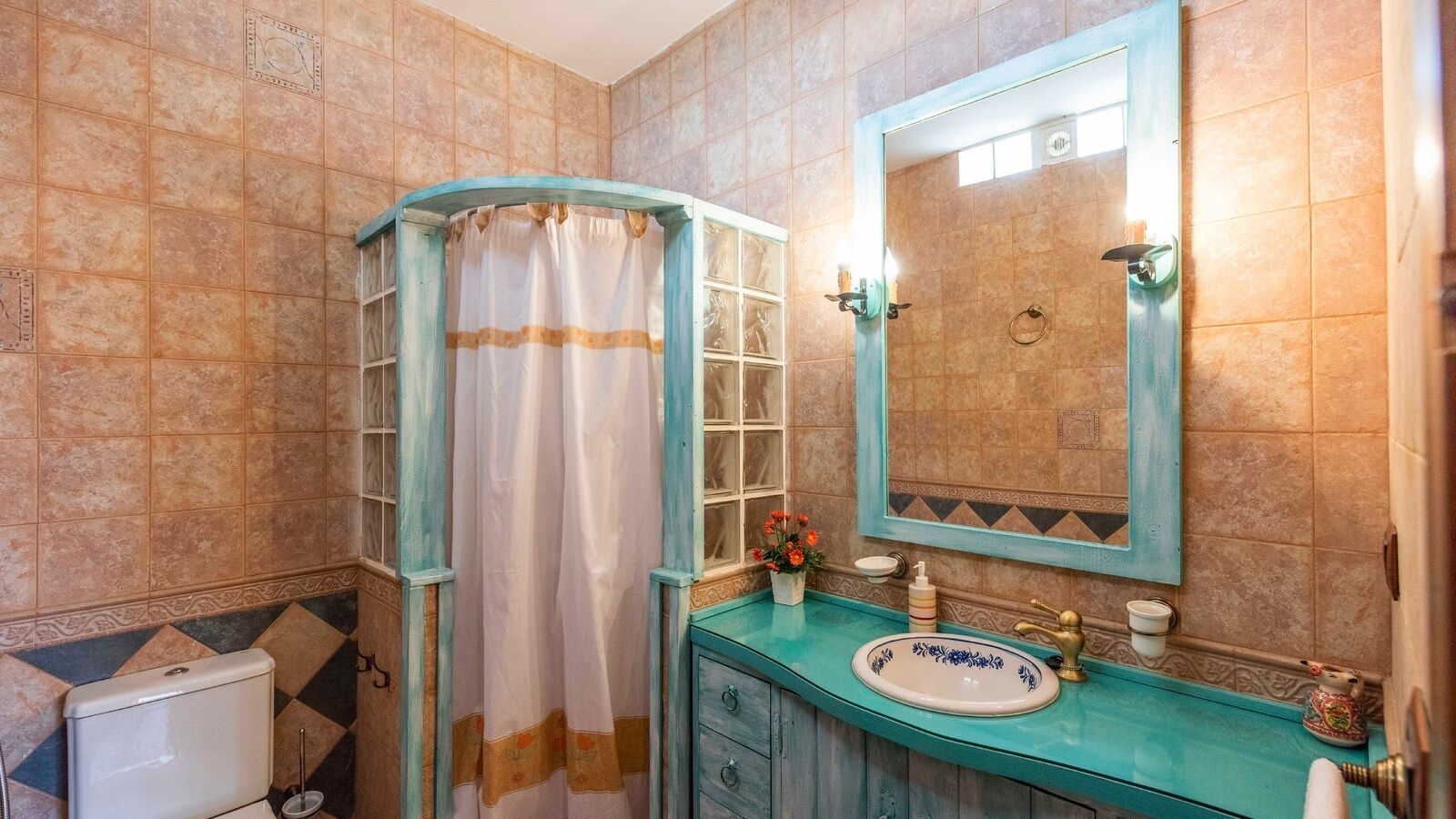 A bathroom with a turquoise sink, a white toilet, and a shower curtain.