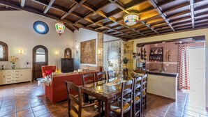 Un amplio salón con mesa de comedor, sofá rojo y vigas de madera en el techo.