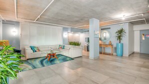 A spacious living area with a white sofa, a coffee table, and a large plant. - Direct Beach Access & View: Satellite Beach Condo! (Satellite Beach)