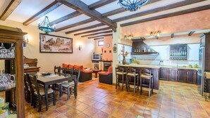 A spacious living area with a dining table, chairs, and a kitchen with a bar. - La Torna Carcabuey by Ruralidays (Córdoba)
