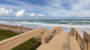 A wooden boardwalk leading to the beach with waves crashing onto the shore.