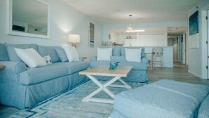 A living room with a light blue sofa set, a coffee table, and a rug.