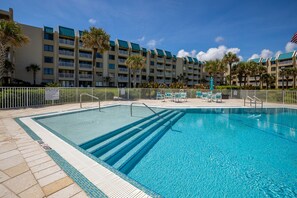 Relax by the pool surrounded by lush palm trees and comfortable lounge chairs.