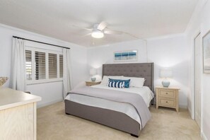 Relax in this serene bedroom with a large bed, bedside tables, and a ceiling fan.