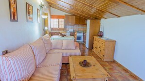 A living room with a striped sofa, a wooden coffee table, and a kitchen in the background. - Sol de Taberno - Ático Tía Beba by Ruralidays (Almería)