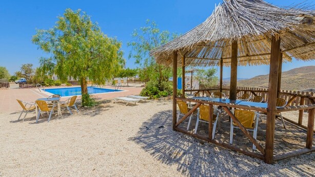A pool area with a thatched gazebo, lounge chairs, and a small pool. - Sol de Taberno - Ático Tía Beba by Ruralidays (Almería)