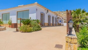 A building with a reception area, a covered outdoor seating area, and a view of a hilly landscape. - Sol de Taberno - Ático Tía Beba by Ruralidays (Almería)