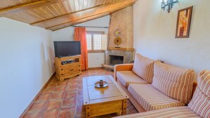 A cozy living room with a wooden TV stand, a sofa, and a fireplace. - Sol de Taberno - Ático Tía Beba by Ruralidays (Almería)