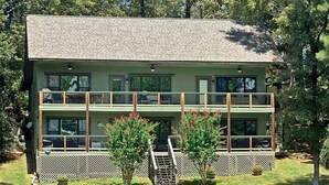 A two-story building with a balcony, a small staircase leading to the entrance, and a dock extending into a body of water.