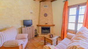 Una sala de estar con sofás a rayas, un televisor sobre un mueble, una chimenea y una ventana con cortinas.