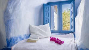 Een kamer met een bed, een raam en een boek.