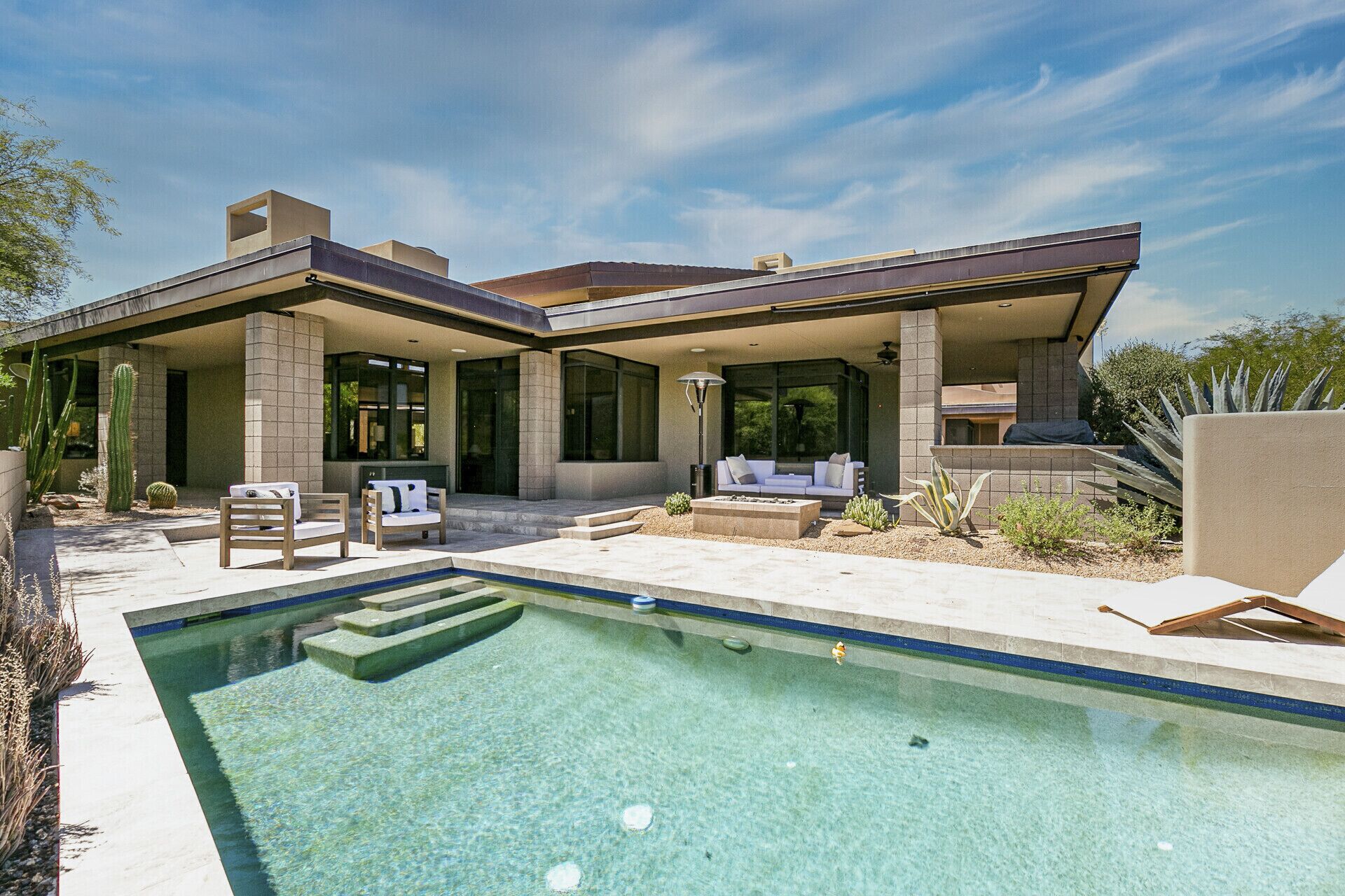 A modern house with a swimming pool, outdoor seating, and a patio area.