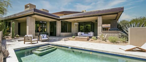 A modern house with a swimming pool, outdoor seating, and a patio area.
