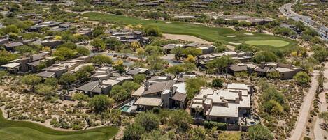 An aerial view of a residential area with houses, green lawns, and a golf course.