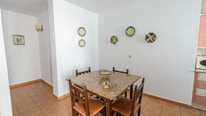A dining area with a table and chairs, a wall-mounted light fixture, and a small picture frame. - Casas María Carmona - Casa Tierra Níjar by Ruralidays (Almería)