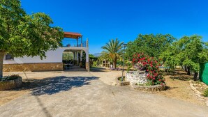 A villa with a covered patio, a stone pathway, and a garden with flowering plants. - Casa Crisal Arriate by Ruralidays (Málaga)