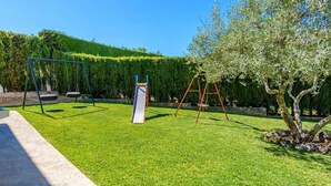 A playground with swings and a slide, surrounded by well-maintained grass and trees. - Casa Crisal Arriate by Ruralidays (Málaga)