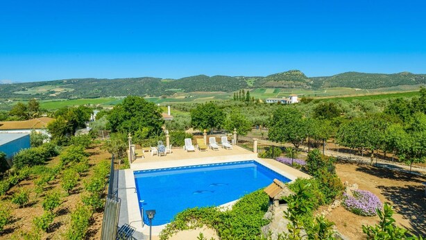 A swimming pool with lounge chairs, surrounded by greenery and vineyards, with a view of rolling hills in the background. - Casa Crisal Arriate by Ruralidays (Málaga)