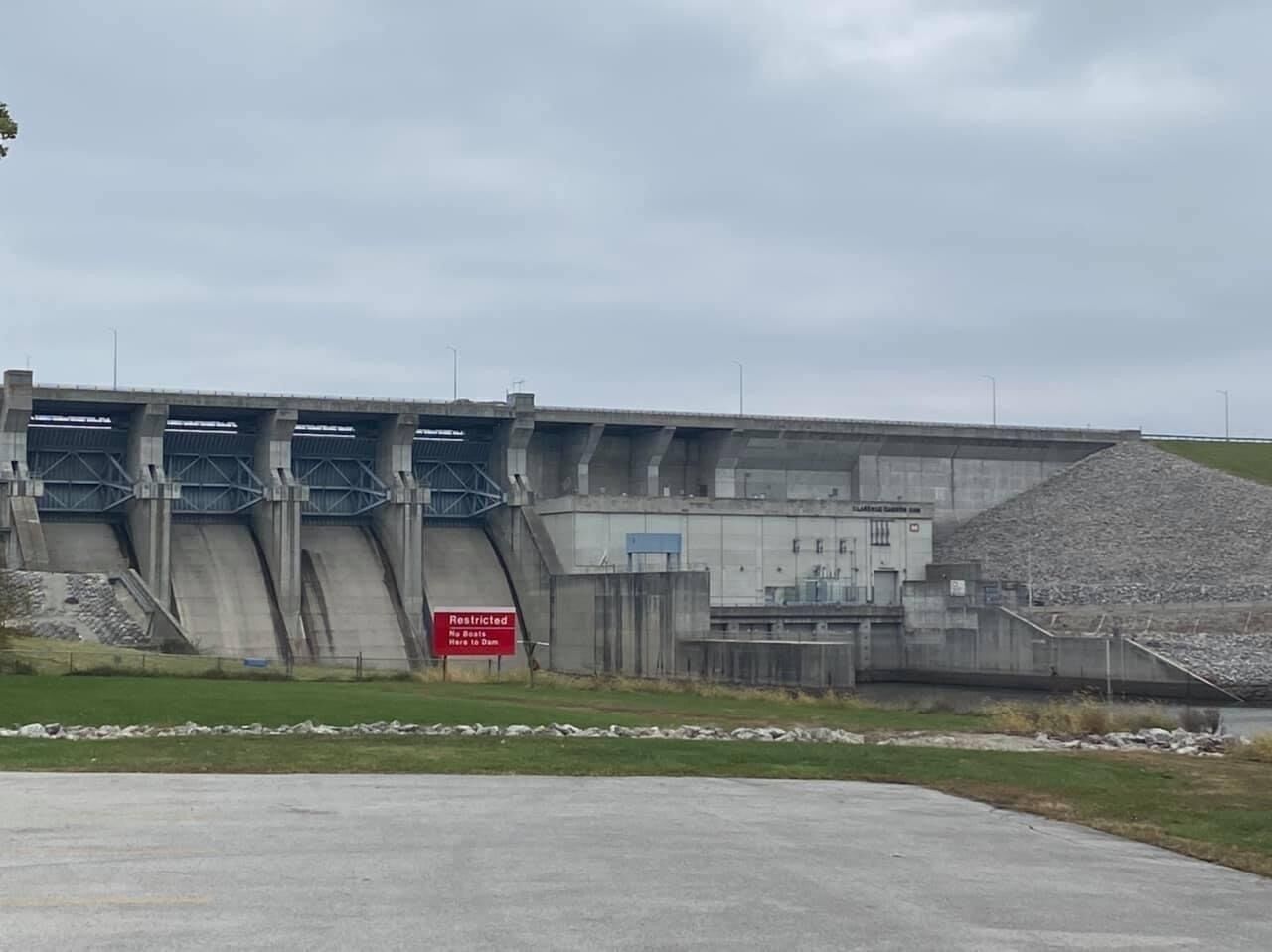 A large dam with a restricted sign, a concrete structure, and a gravel pile.