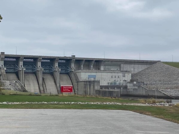 Una gran presa con un letrero de acceso restringido, una estructura de concreto y un montículo de grava.