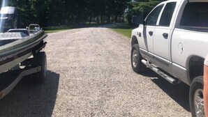 A gravel driveway leading to a white pickup truck parked on the side.