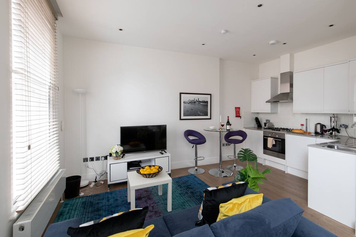 A modern apartment with a living room, dining area, and kitchen.