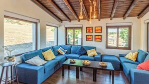 A living room with a blue sectional sofa, a coffee table, and a wooden ceiling.