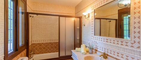 A bathroom with a bathtub, a sink, a mirror, and a shower.
