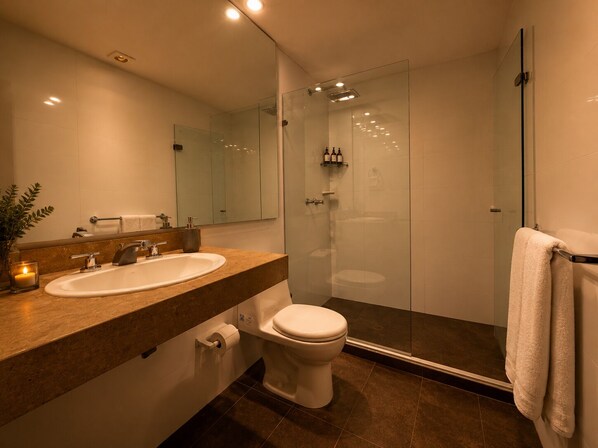 Un baño moderno con ducha acristalada, lavabo blanco y retrete.