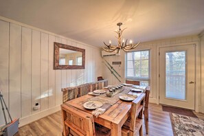 A dining area with a wooden table, chairs, a chandelier, and a large mirror on the wall. - < 1 Mi to Beech Mtn Ski! Condo w/ Hot Tub Access (Beech Mountain)