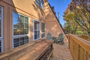 A wooden deck with a table and chairs, a covered area with a bench, and a view of trees and a building. - < 1 Mi to Beech Mtn Ski! Condo w/ Hot Tub Access (Beech Mountain)