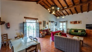 Uma sala de estar espaçosa com uma mesa de jantar, sofás e uma televisão.