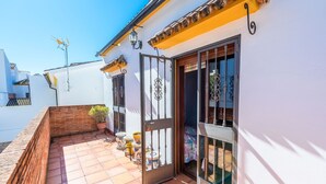 Un edificio blanco con un patio empedrado, una reja metálica y una planta en maceta.