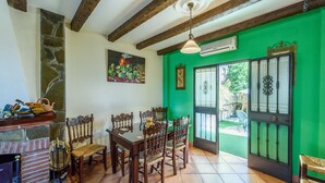 Un comedor con una mesa y sillas de madera, una chimenea de piedra y una pared verde.